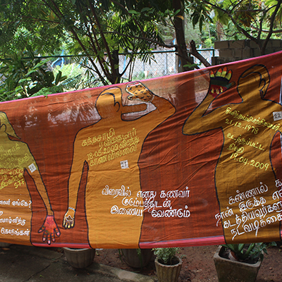 Red banner painted with orange people covered in white and yellow writing