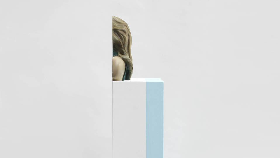 Sliced figurative sculpture on white plinth with vertical blue stripe