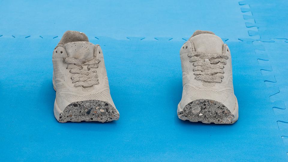 Concrete cast of a pair of trainers with the toe missing