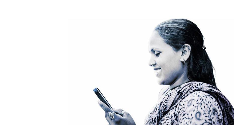 Lady looks at mobile phone whilst smiling.