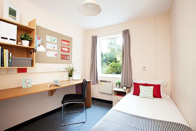A student bedroom with bed, desk and noticeboard