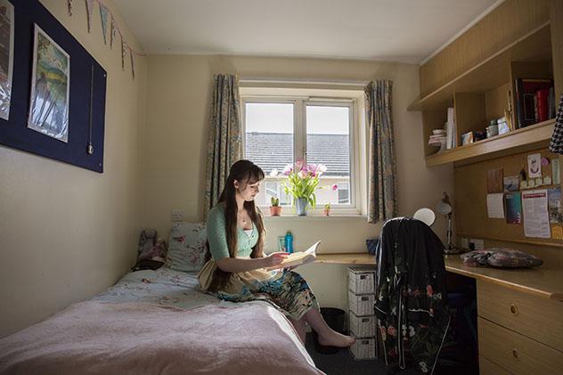 A female student sitting on a bed in halls