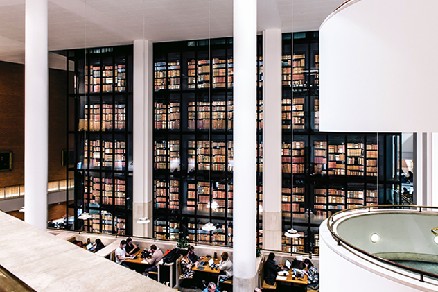 Wide image of British Library bookshelves with people working at desks