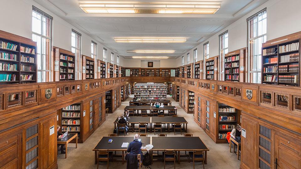 The interior of Senate House Library with rows of books along the walls and desks running along the centre of the room
