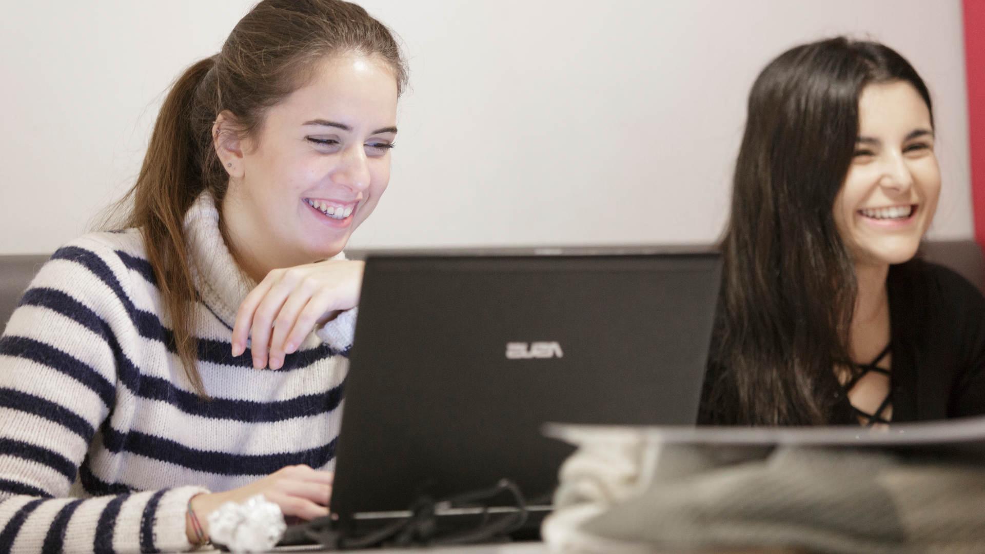 Smiling female students using laptops