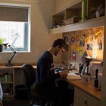 A male student sitting at his desk in his university room