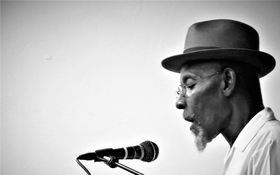 A black and white image of a man performing into a microphone.