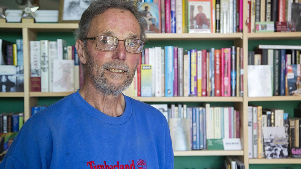 A photograph of Geoff Hardy standing in front of book shelves