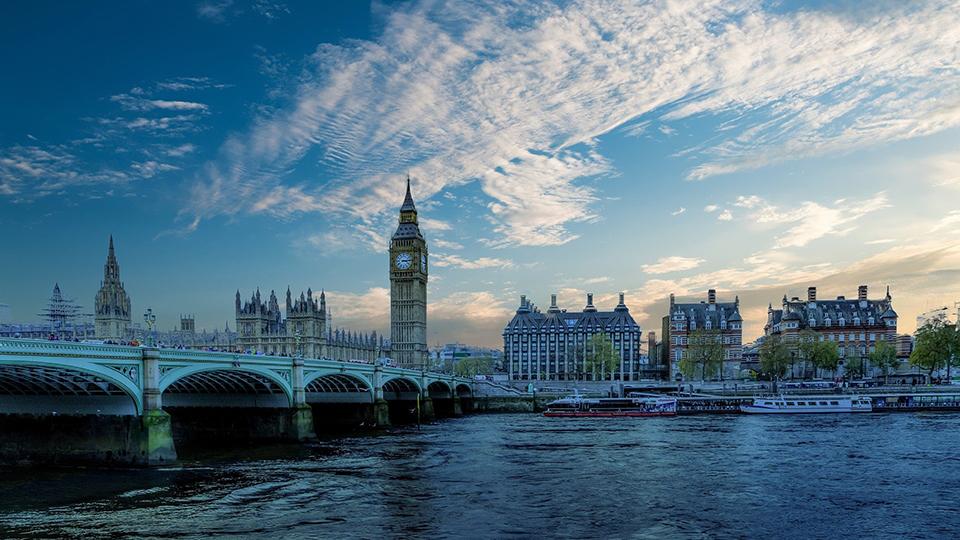 Image is a panoramic scene of the Thames and Palace of Westminster (home to the Commons and Lords) including the Big Ben clock tower 