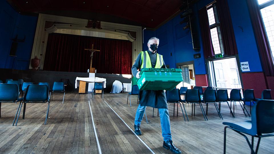 Man carrying crate of donations in a church.