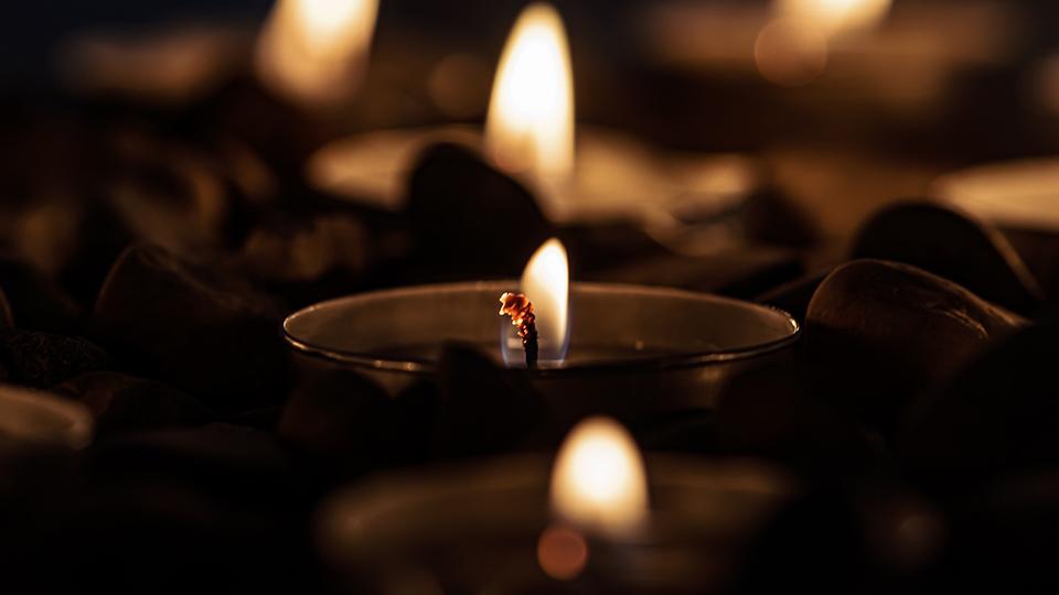 Image shows three tealight candles, traditionally lit in churches to remember the dead