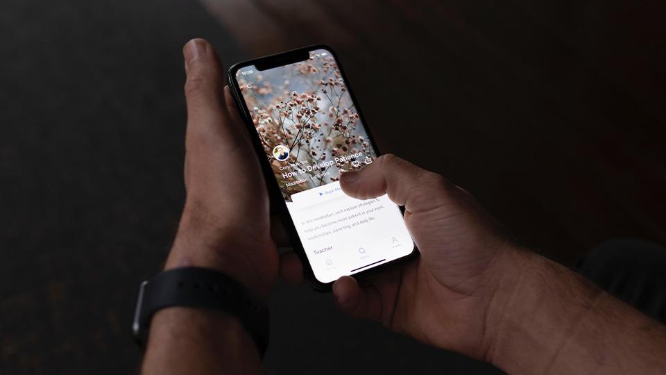 An image of a person holding a mobile phone with a mindfulness app open
