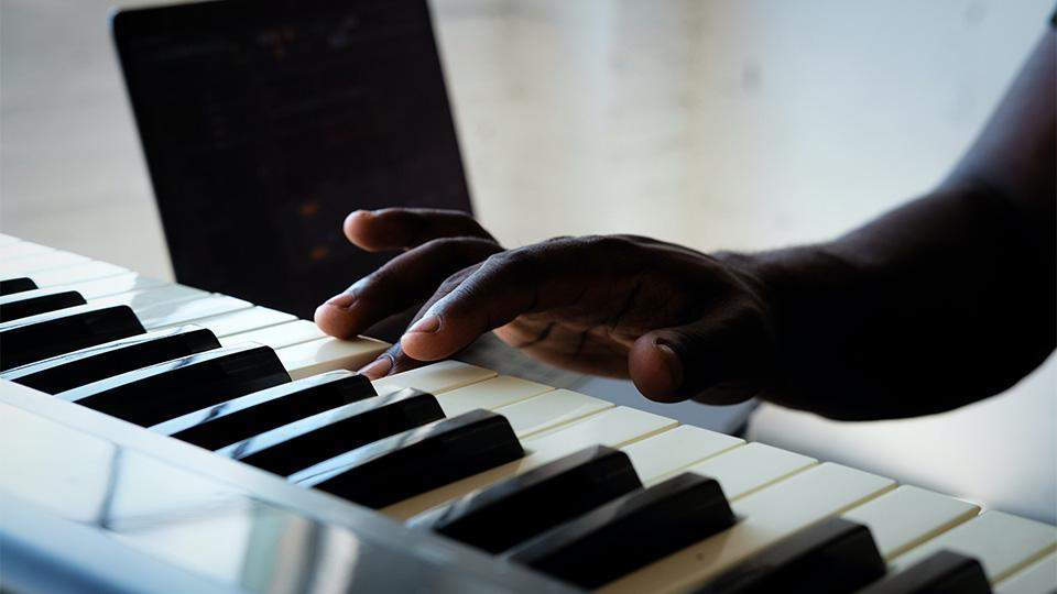 Stock image of someone playing the keys of a piano