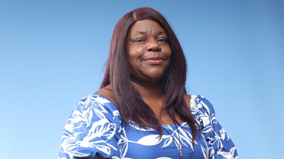 Black female, long red/black hear wearing a pale blue dress with white print