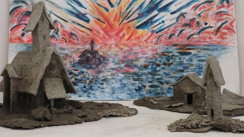 Sculptures houses in grey clay against a colourful (blue and pink) painted skyscape 