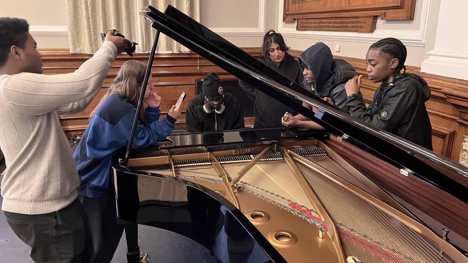 Young people gather around the piano