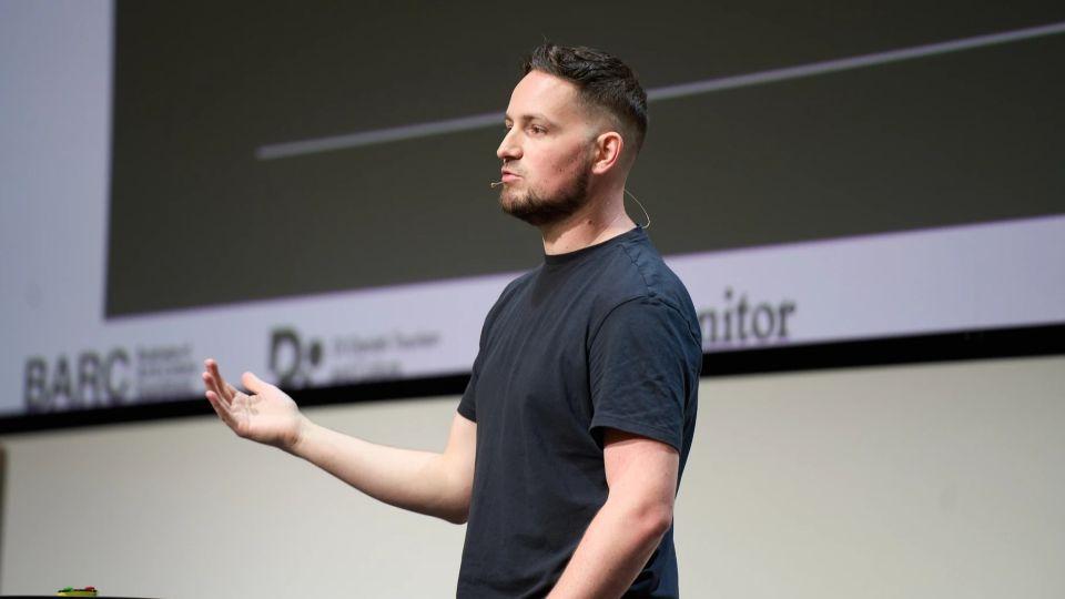 Dr George Musgrave, wearing a black T-shirt, presenting at a conference