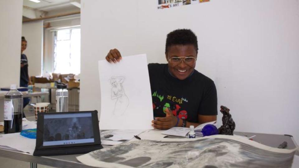 Young male artist proudly holds up his sketch