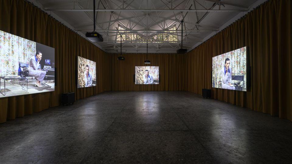 A large room with four screens showing the same scene from different angles