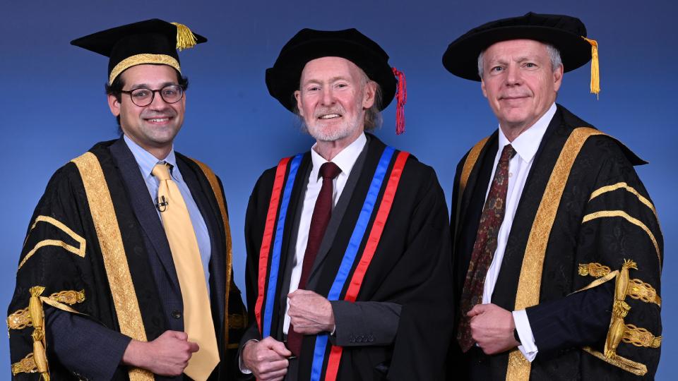 Three man in ceremonial outfits pose for graduation ceremony portrait