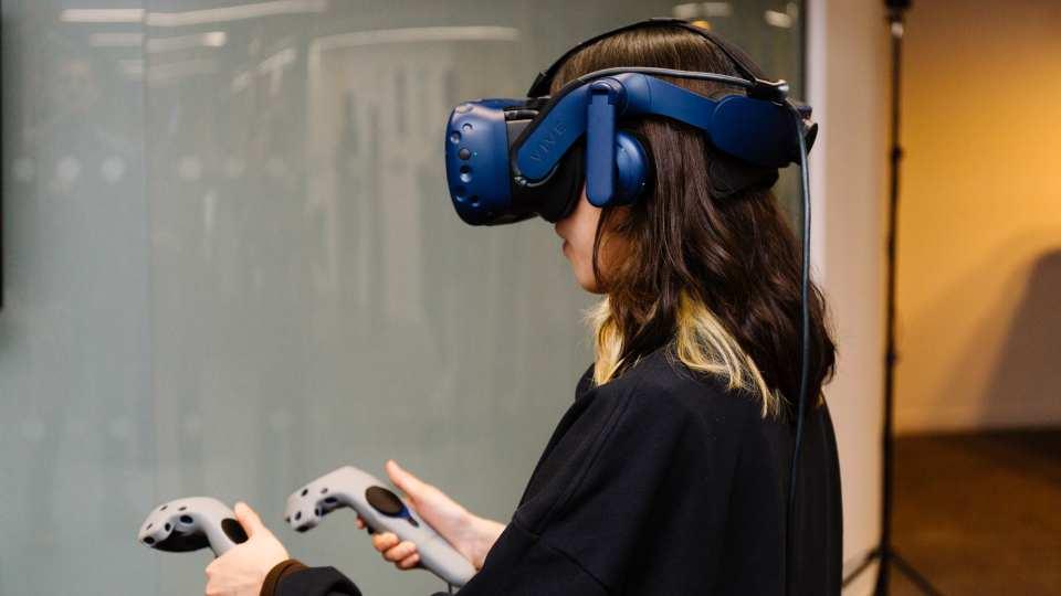Young female wearing virtual reality headset works with handsets