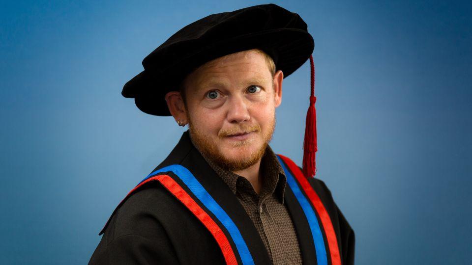 Kae Tempest portrait photo wearing academic cap and gown 
