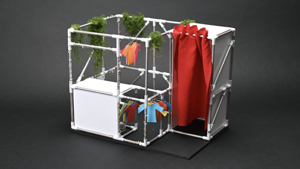 A model of a pop-up stall selling clothes using scaffolding as the frame