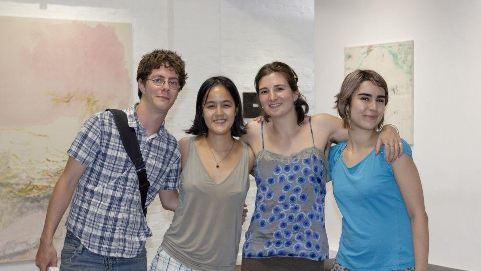 The four graduates standing in a line with their arms around each other