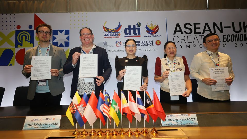 Five people holding up papers standing behind a desk 