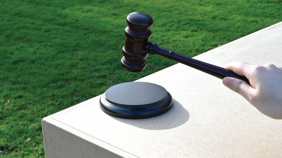 A hand holding a gavel on top of the podium