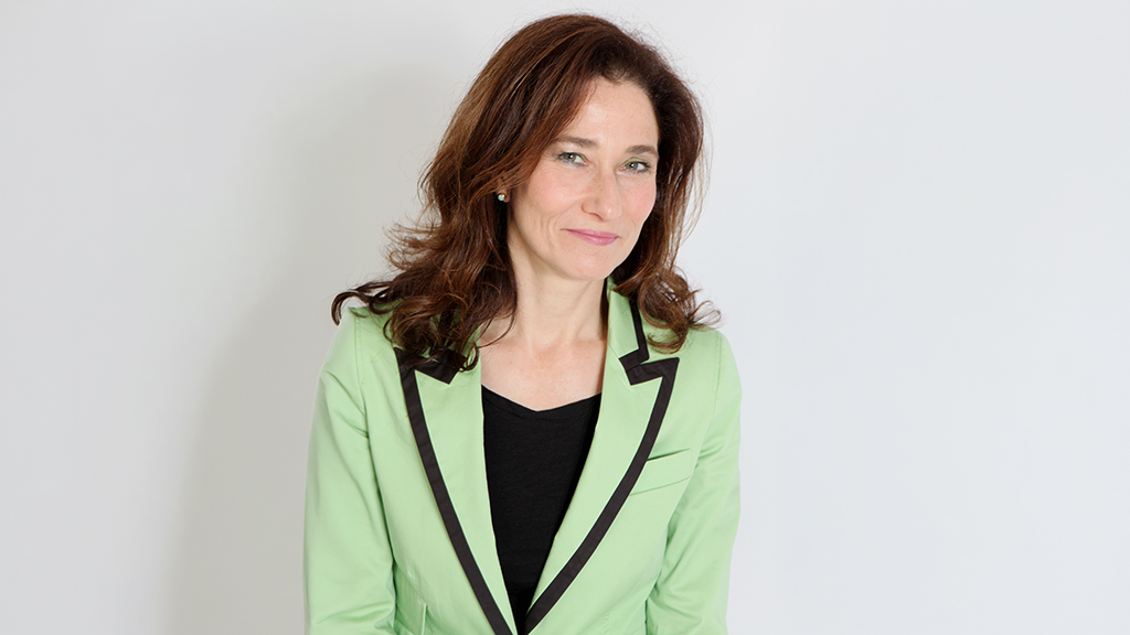 A portrait photograph of Joanna Newman wearing a green jacket and black top