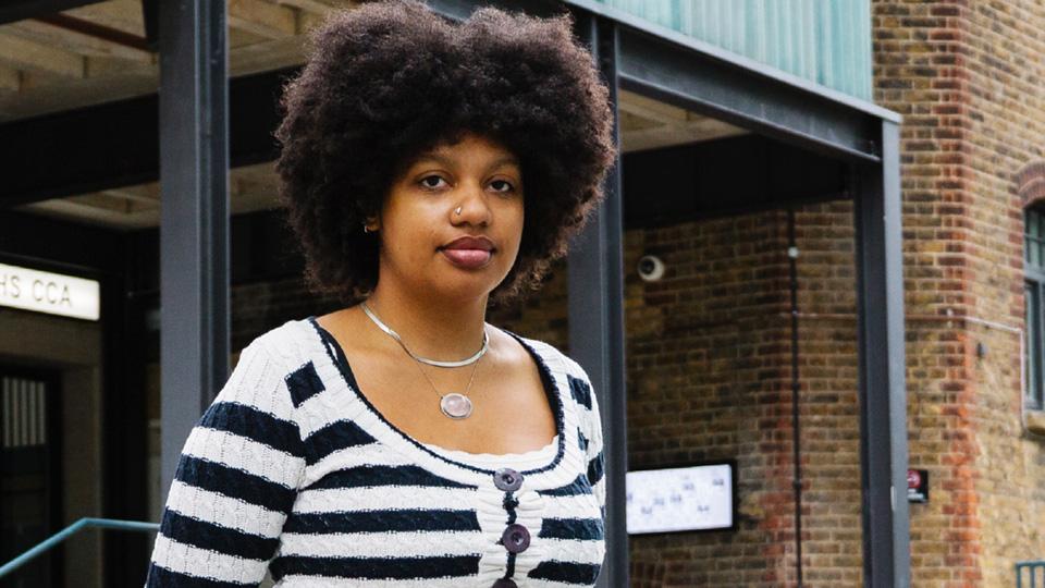 A woman stands infront of a contemporary art gallery.