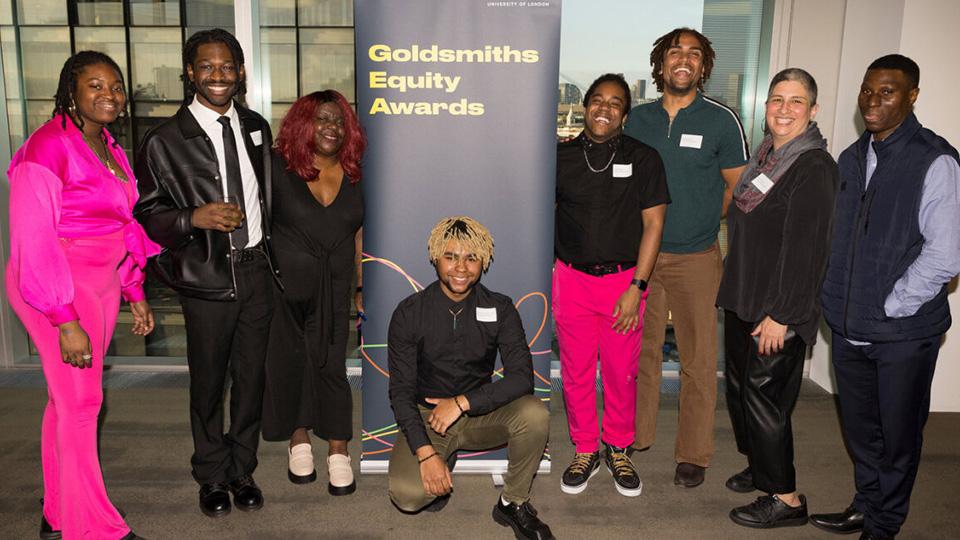 Eight people pose for the camera in front of a sign that reads 'Goldsmiths Equity Awards'