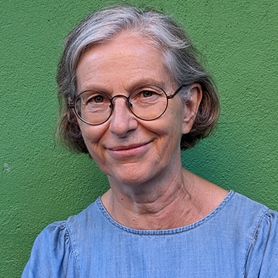 Headshot of Professor Kate Nash smiling and standing against green background