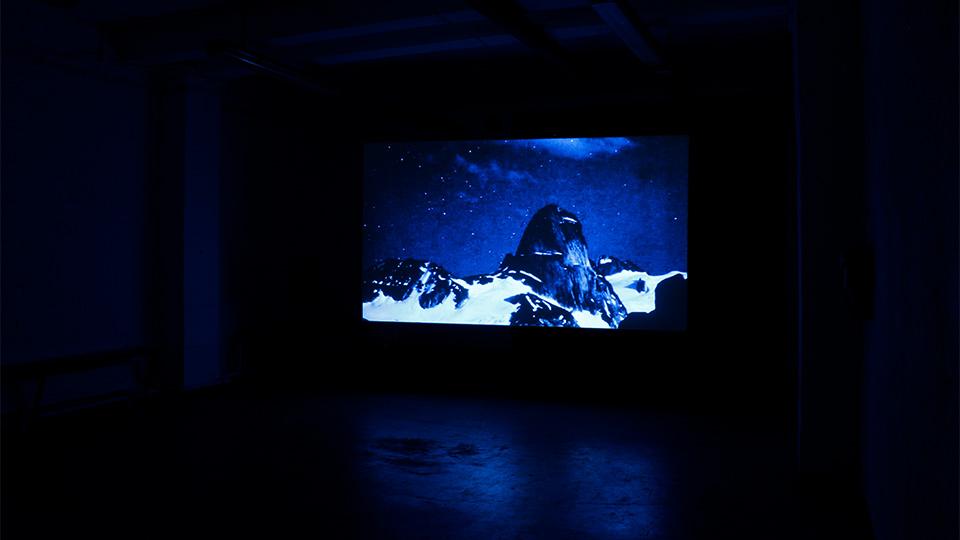 A screen in a dark room showing an image of the Andes