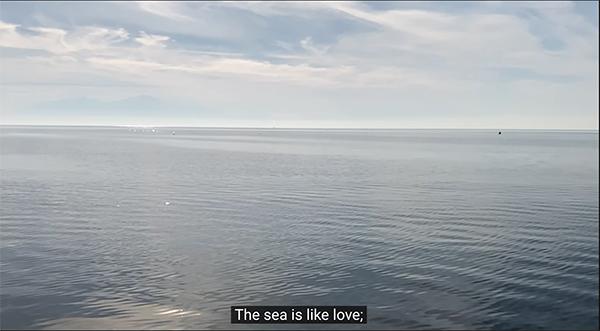 Video still of seawater with a blue sky with text subtitle reading 