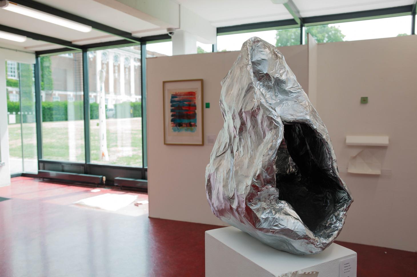 A sculpture displayed on a white pedestal, showcasing intricate details and artistic design