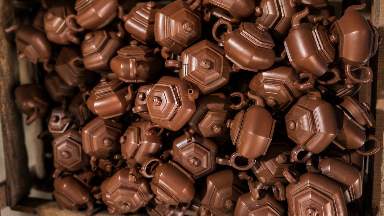Lots of identical brown teapots in a box