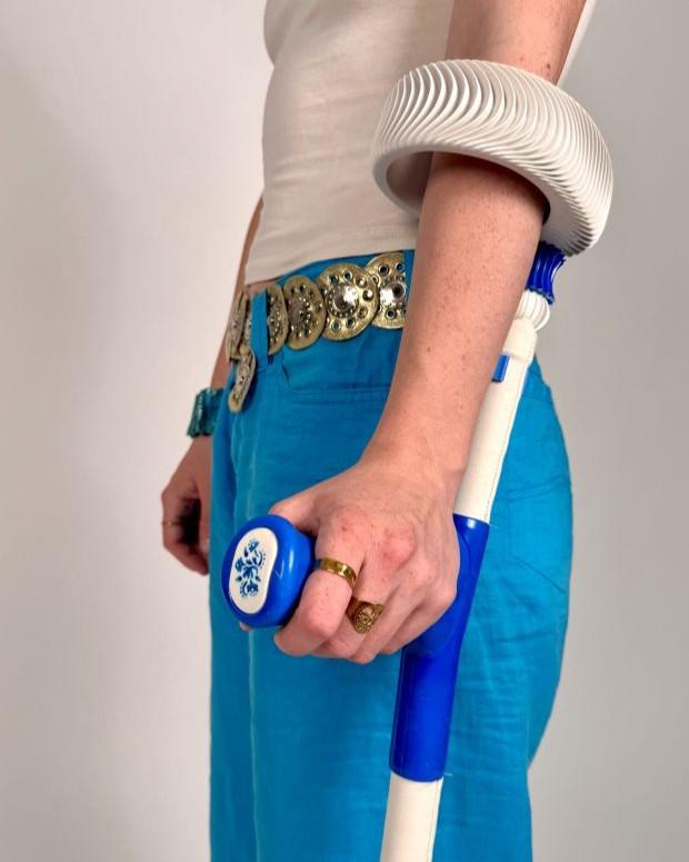 The side view of somebody using a blue and white forearm crutch