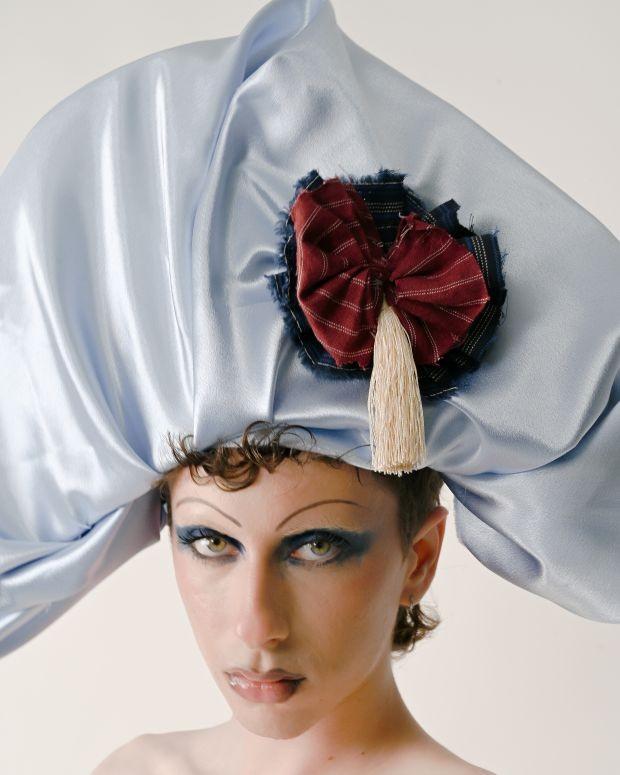 A model wearing a blue silk oversized hat with a rosette 