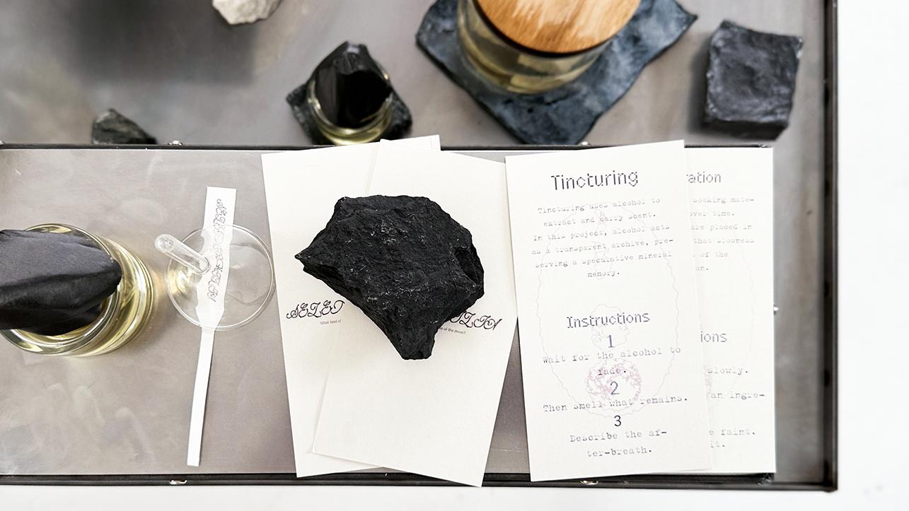 A selection of objects including rocks on a metal table surface with some printed instructions. 