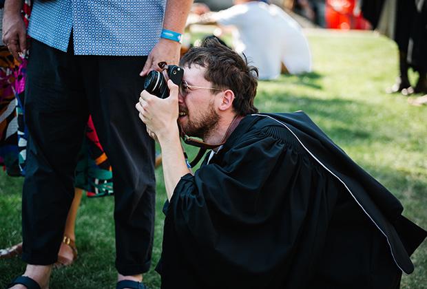 A grad kneels down to take a photo