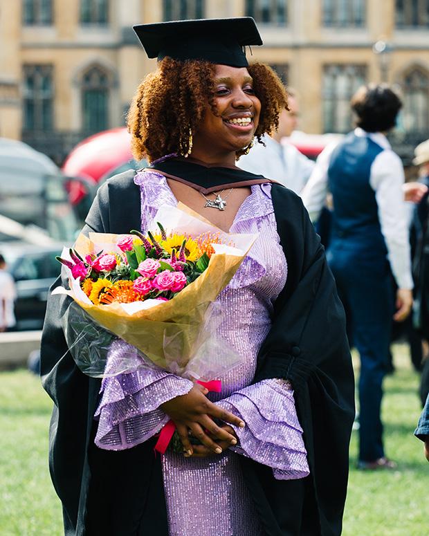 Grad in a purple dress holding flowers
