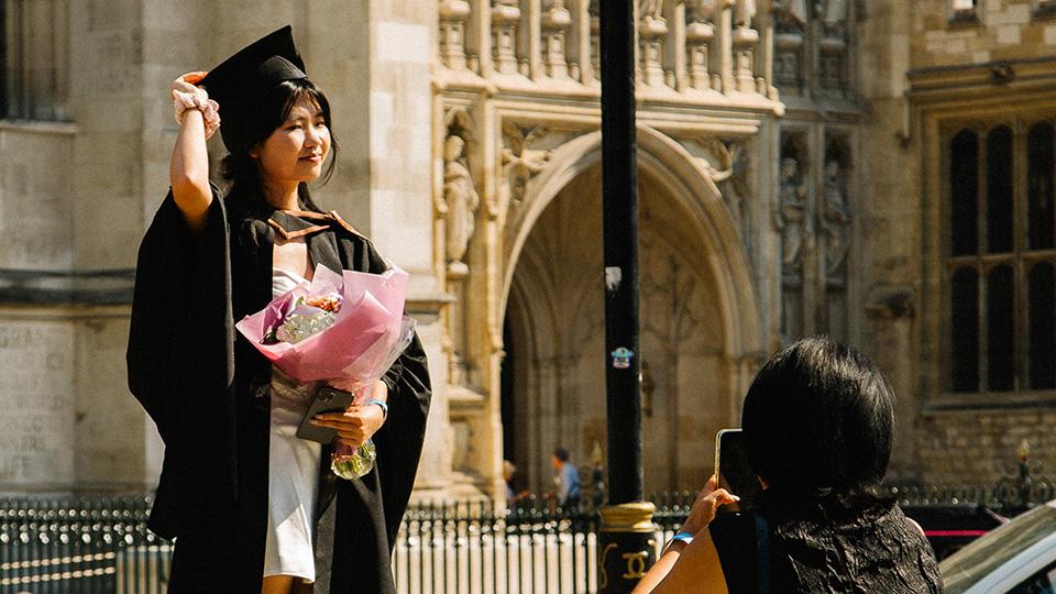 Graduate stands on a step to get her photo taken