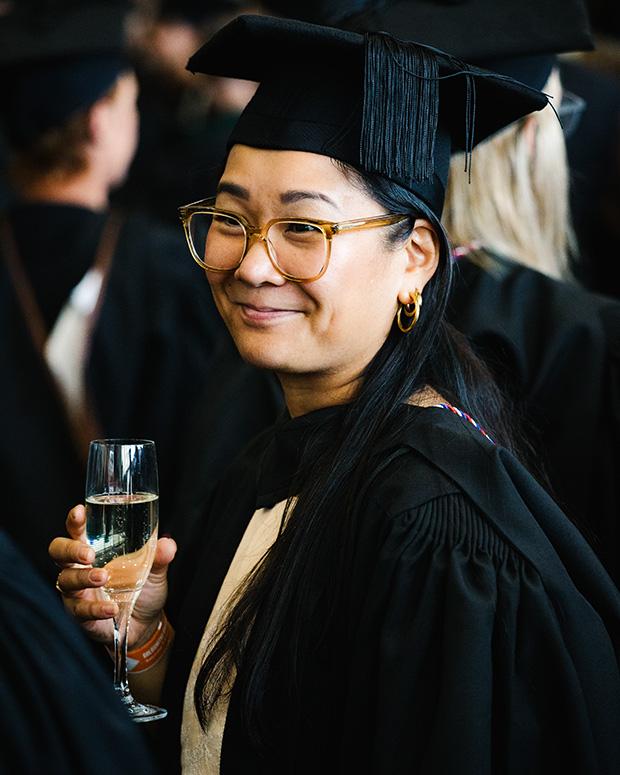 Another grad smiling holding a glass of fizz