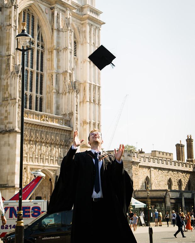 A graduate in front of Westminster Cathedral throwing his hat in the air