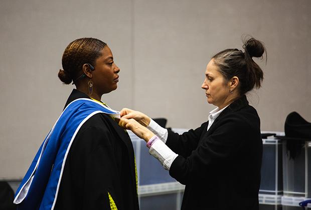 A graduand gets her cloak fitted onto her