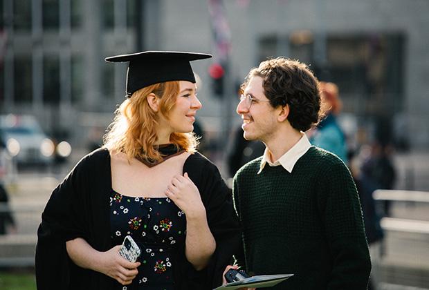 A graduate and friend look into each others eyes