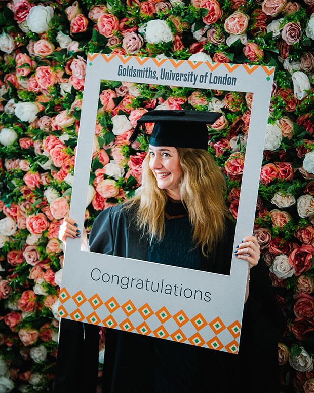 Graduate smiles as her photo is taking holding up a Goldsmiths frame