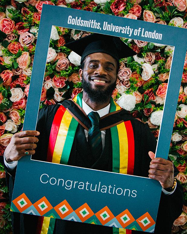 A graduate holds up a Goldsmiths frame for a photo